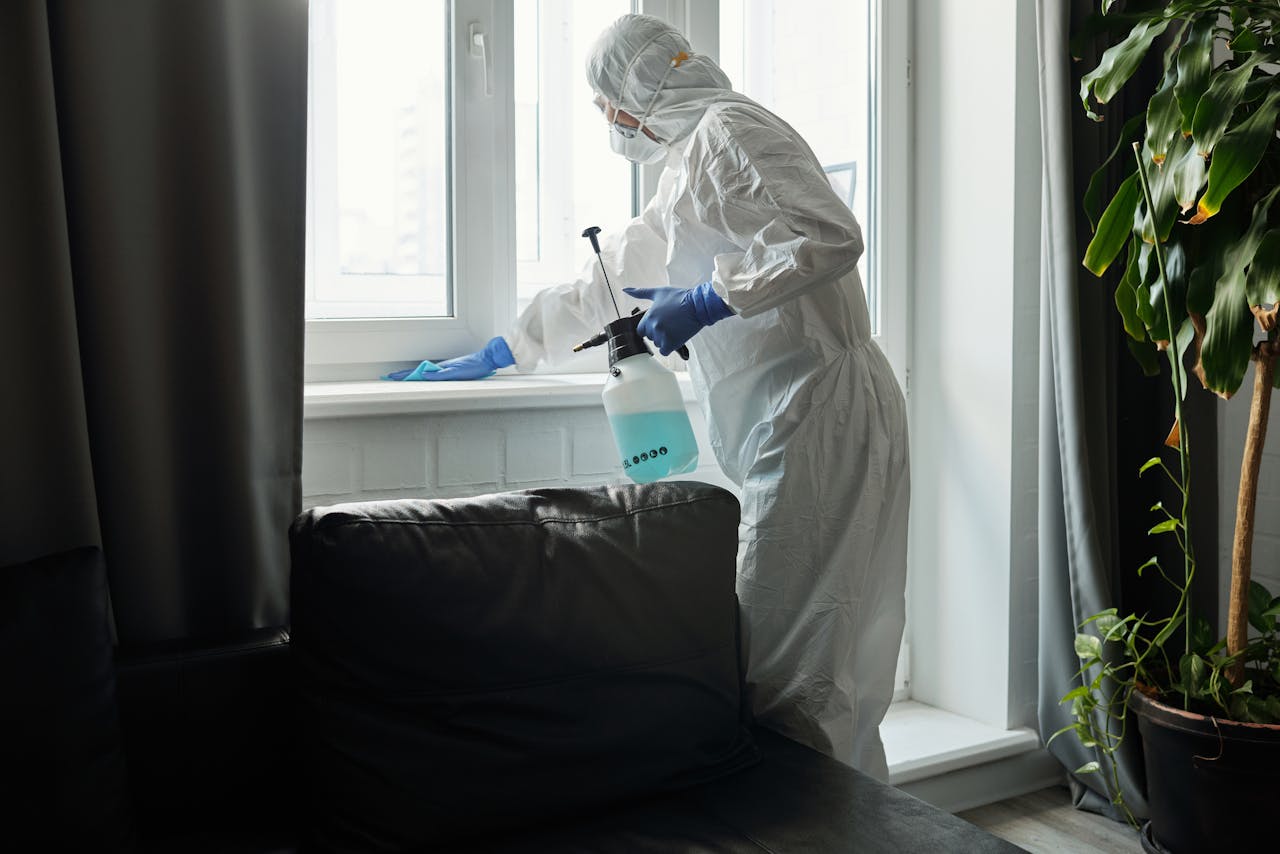 services-02 Person in PPE disinfecting indoor window area during COVID-19 pandemic.